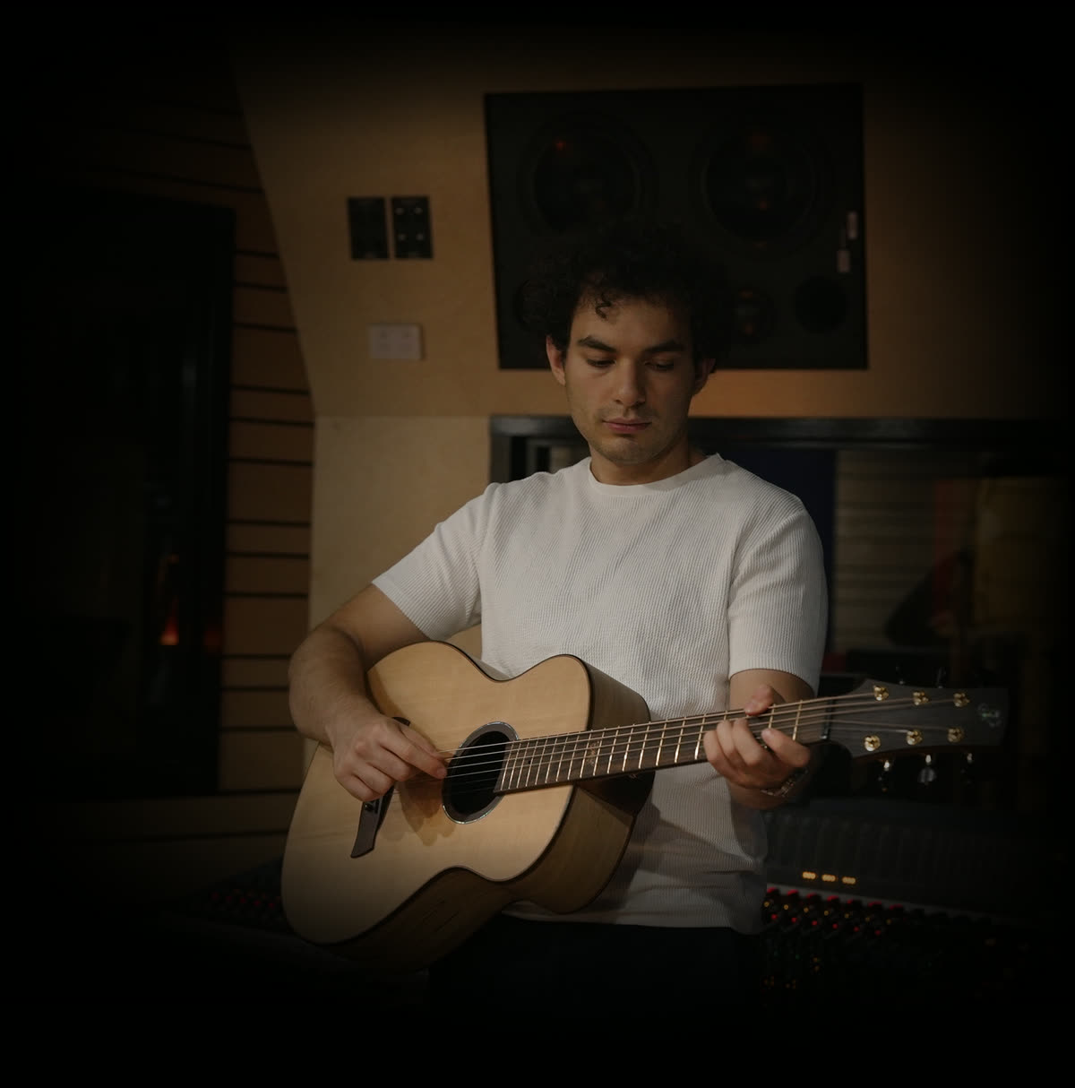 Mert Boyali playing acoustic guitar at a studio console